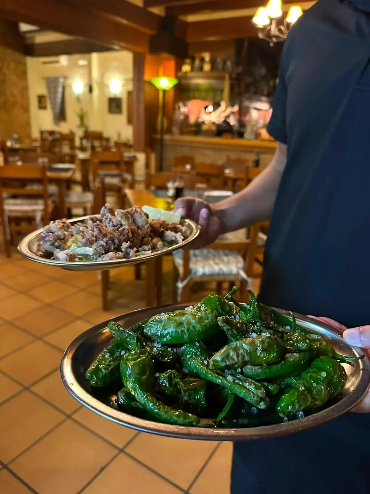 Camarero sirviendo pimientos de Padrón en el comedor