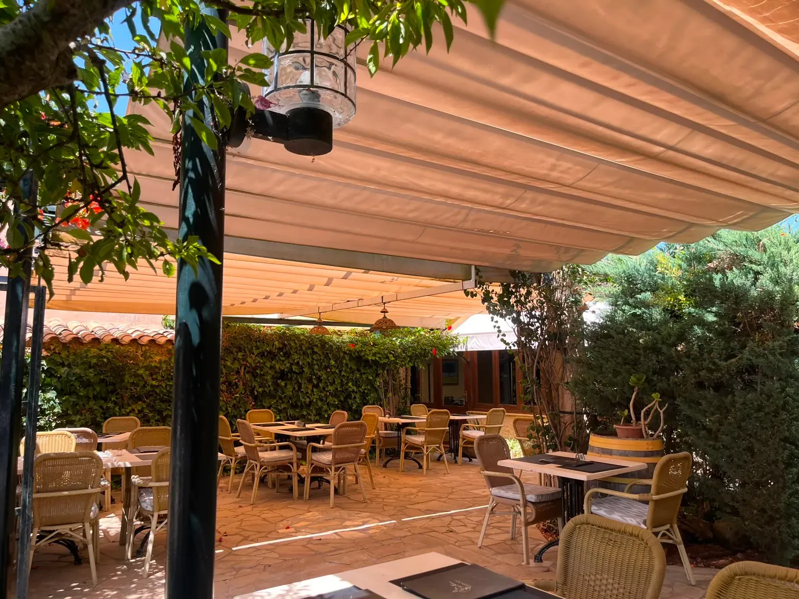 Terraza cubierta con toldo y mesas a la sombra